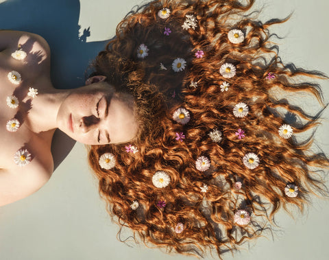 Image of a woman with curly reddish hair, with vegan dye